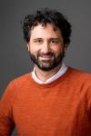 A white male with a beard and mustache, orange sweater